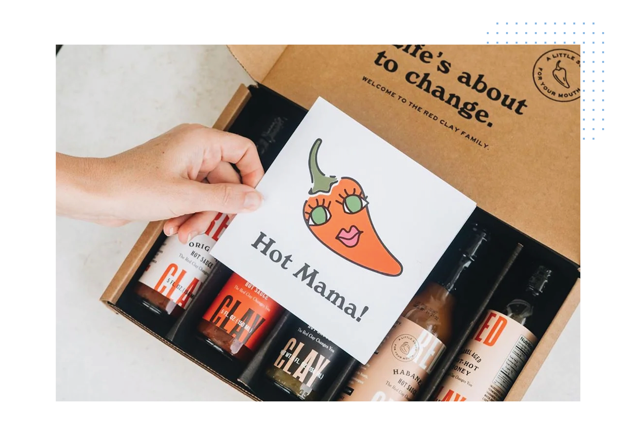 Hand holding Hot Mama card over Red Clay sauces